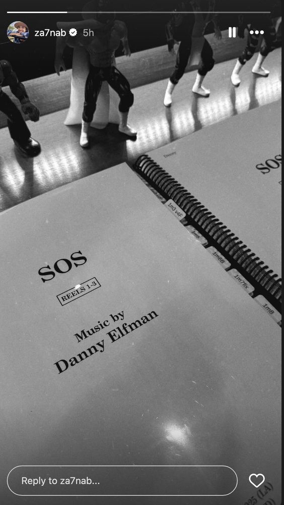 b&w photo of a spiral-bound notebook opened to a page that reads "SOS - Reels 1-3 - Music by Danny Elfman" 