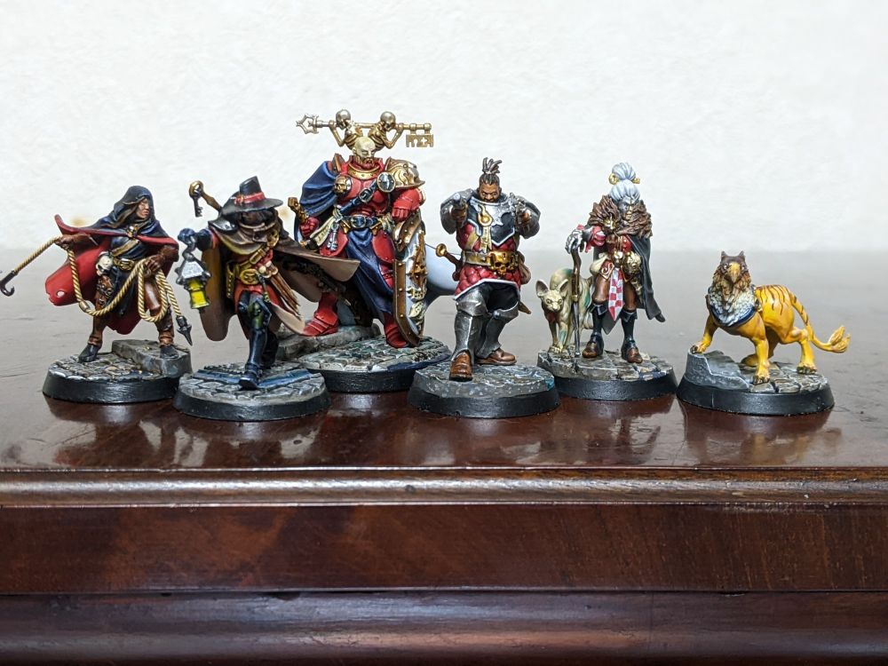  A set of six miniatures. A woman wearing a cloak and  preparing to throw a grapple. A witch hunter with a lantern. A Stormcast with a large key on his back. A fighter with two handguns. An old lady with a gauntleted hand holding a cane and  a  pet cat. A small gryphhound. 