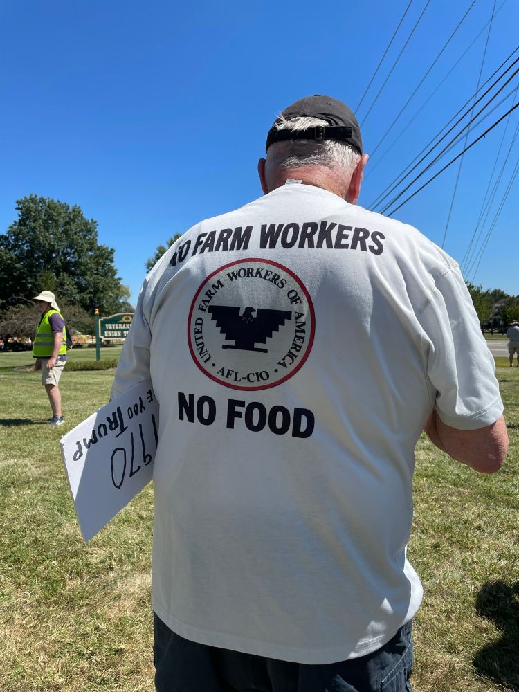 Back of person wearing a t-shirt saying “No Farm Workers No Food”
