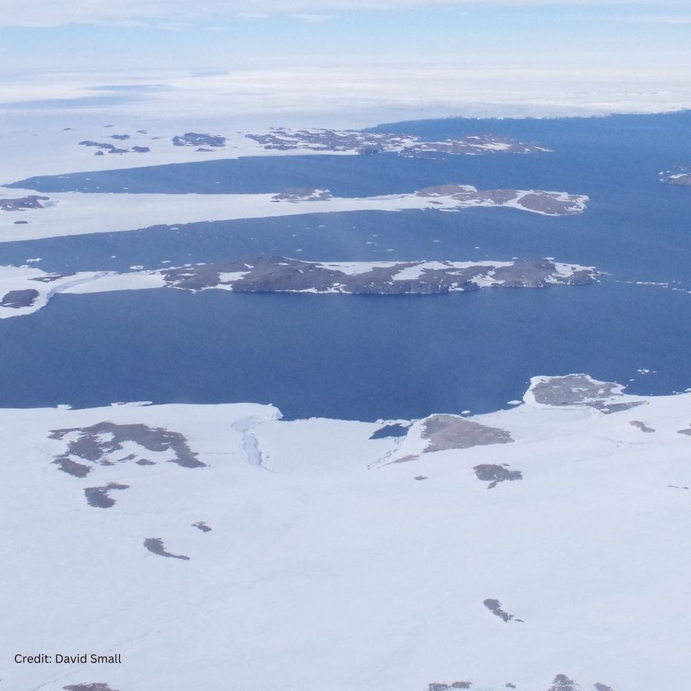 A snow and ice covered rocky landscape next to the sea.