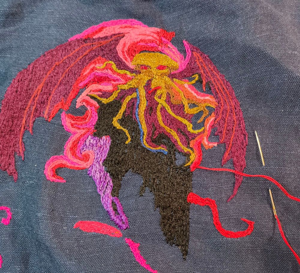 Embroidered depiction of Cthulhu in greens with magenta wings and various shades of pink flames.