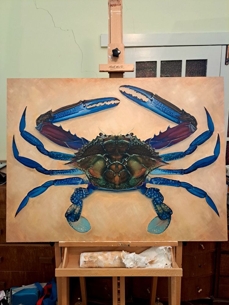 An acrylic painting of a blue swimmer crab showing the full body. The painting is on an easel.