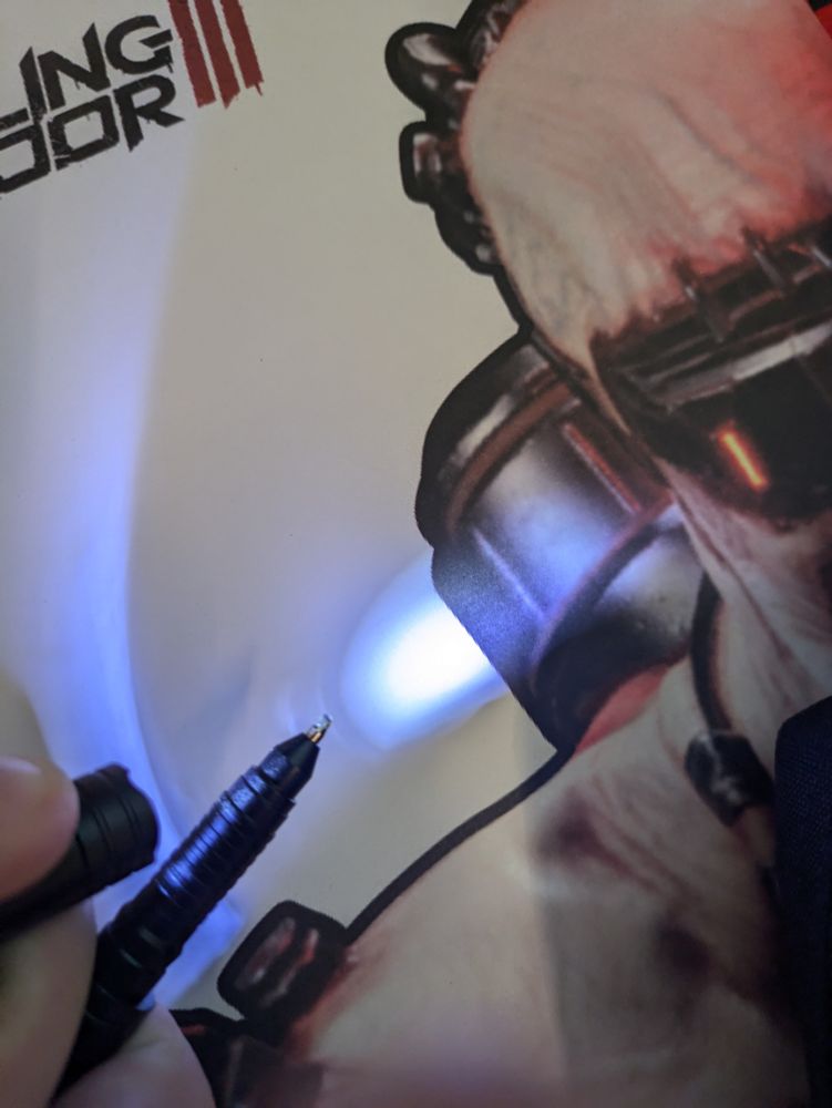 An in-action shot of an opened emergency pen, shining the LED flashlight in the cap on the pen point