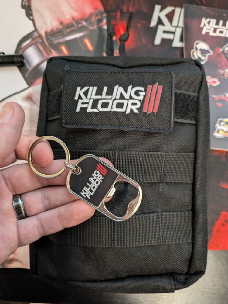 A keychain bottle opener and a square black bag, both with the Killing Floor 3 logo upon them