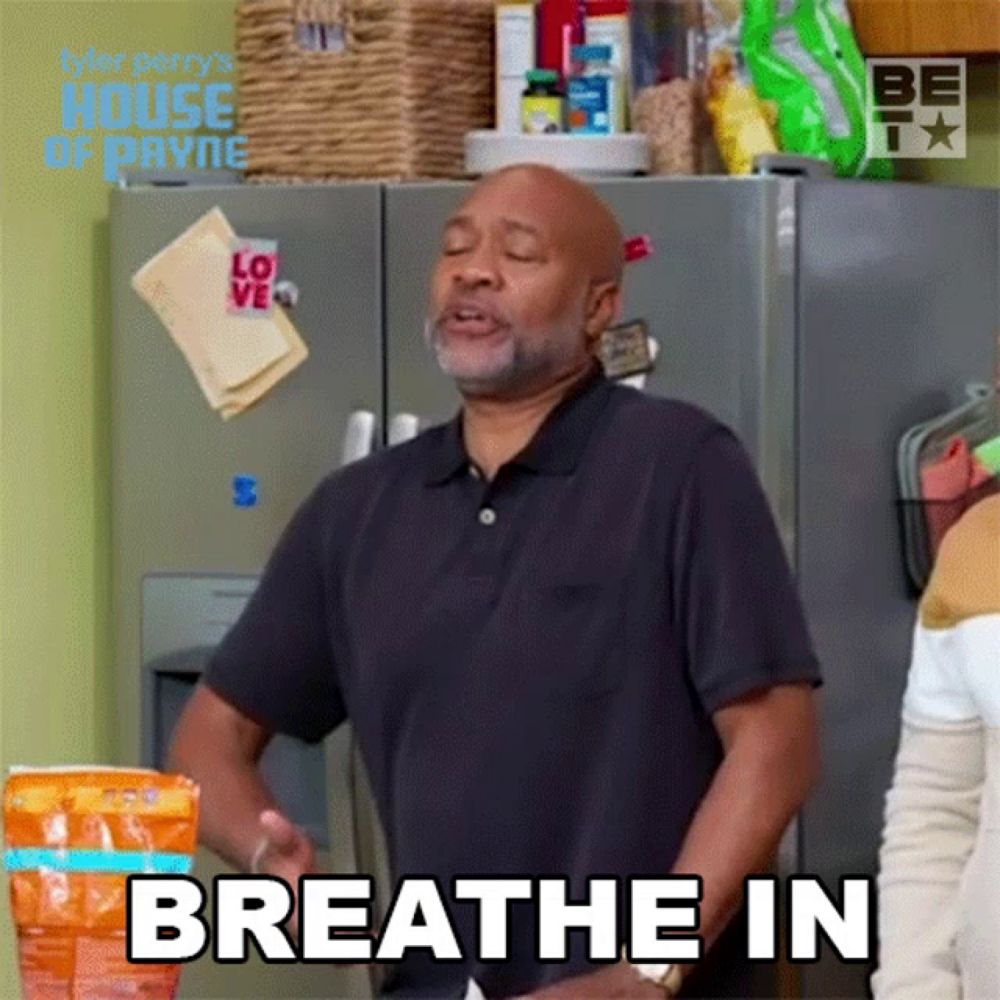 a man is standing in front of a refrigerator with his eyes closed and says breathe in .