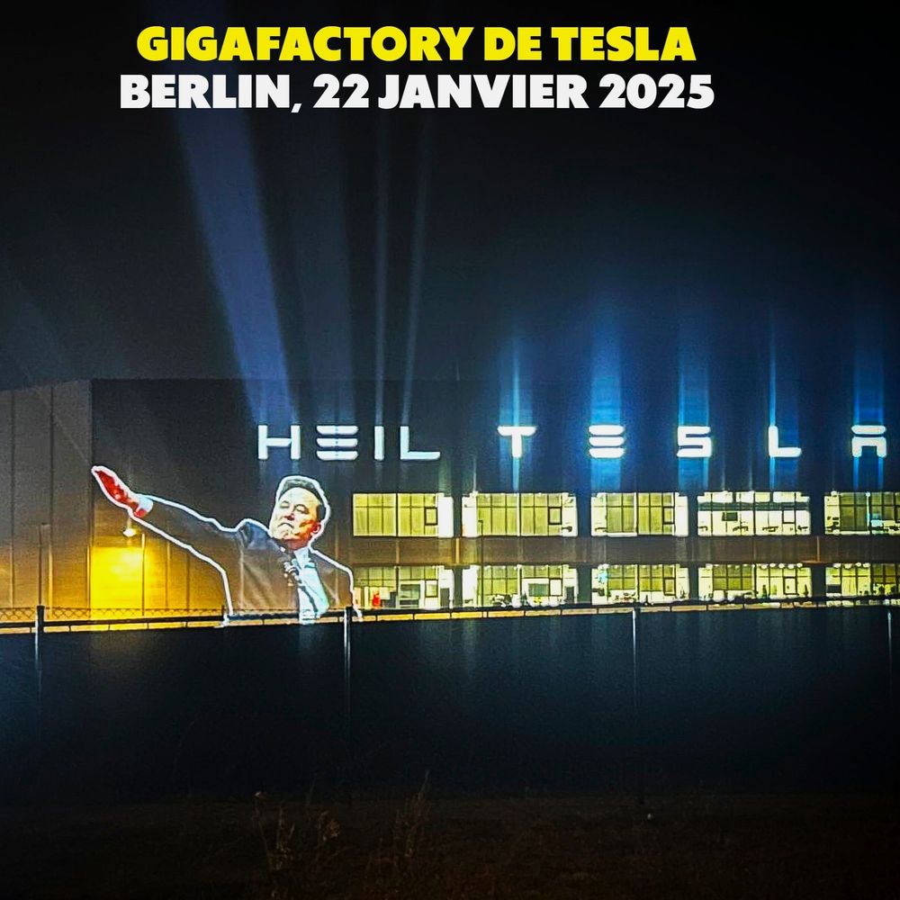 Image d'Elon Musk effectuant un salut nazi, projetée sur la Gigafactory, ou les lettres "Heil Tesla" apparaissent