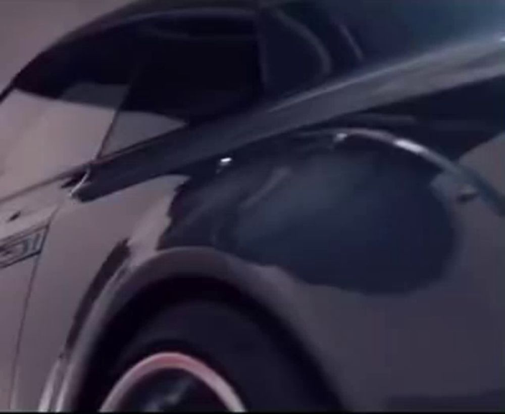 a close up of a black car with a red tail light in a parking garage .