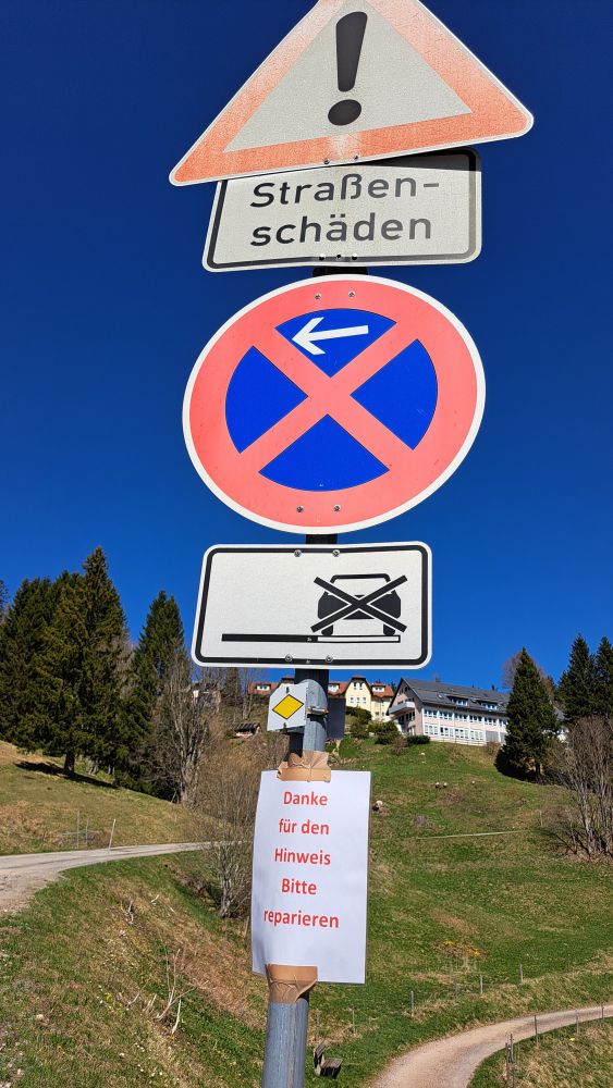 Verkehrsschild: Straßenschäden
Darunter ein Zettel von jemanden: 
Danke für den Hinweise. Bitte reparieren.