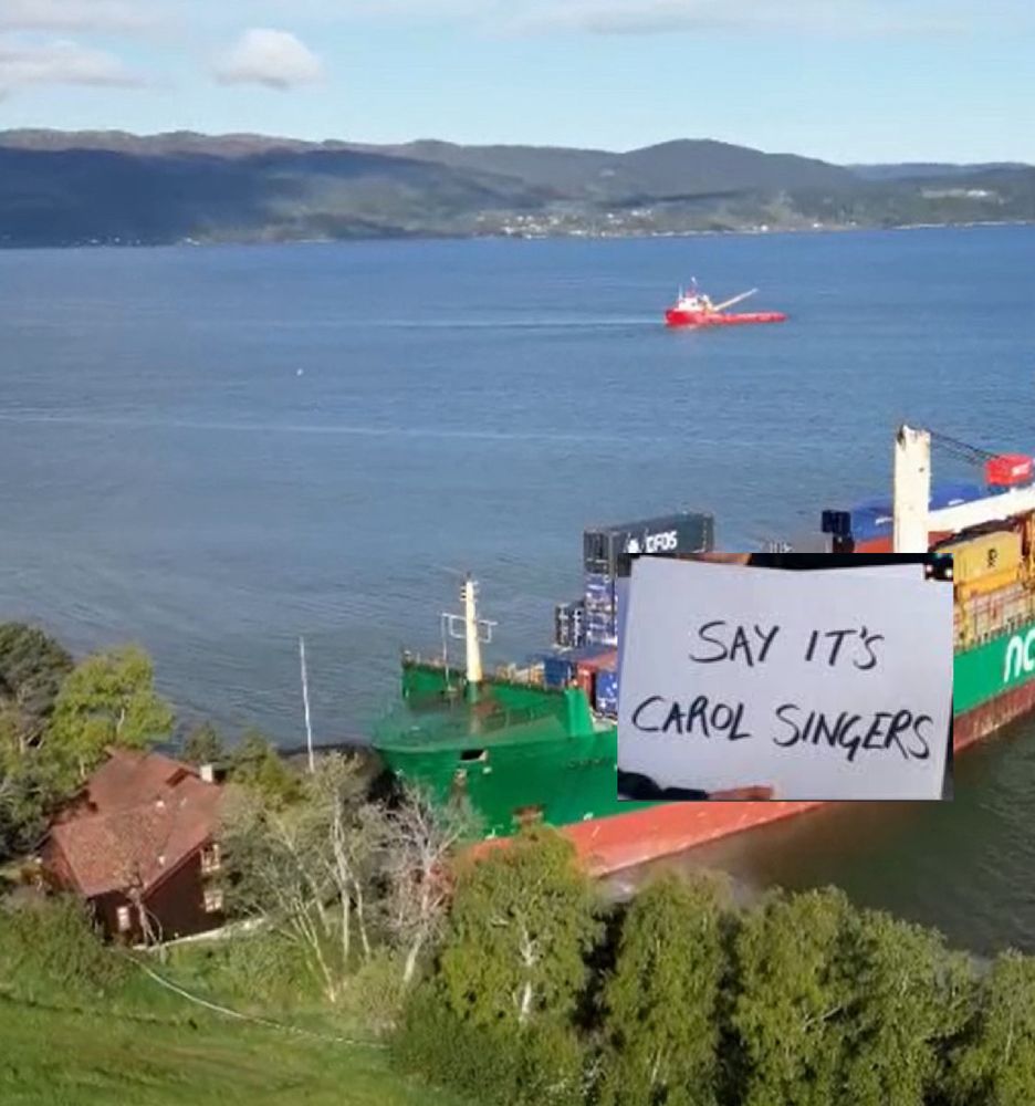 Ship crashed outside a house holding a sign: Say it’s Carol Singers