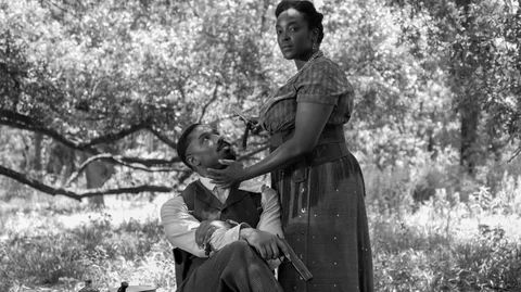 Smoke, seated, looks up at Annie. Annie, standing, cradles Smokes's face in her hands.