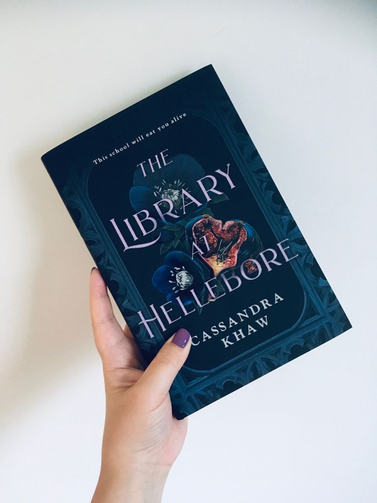 Holding a copy of The Library at Hellebore by Cassandra Khaw (HC)