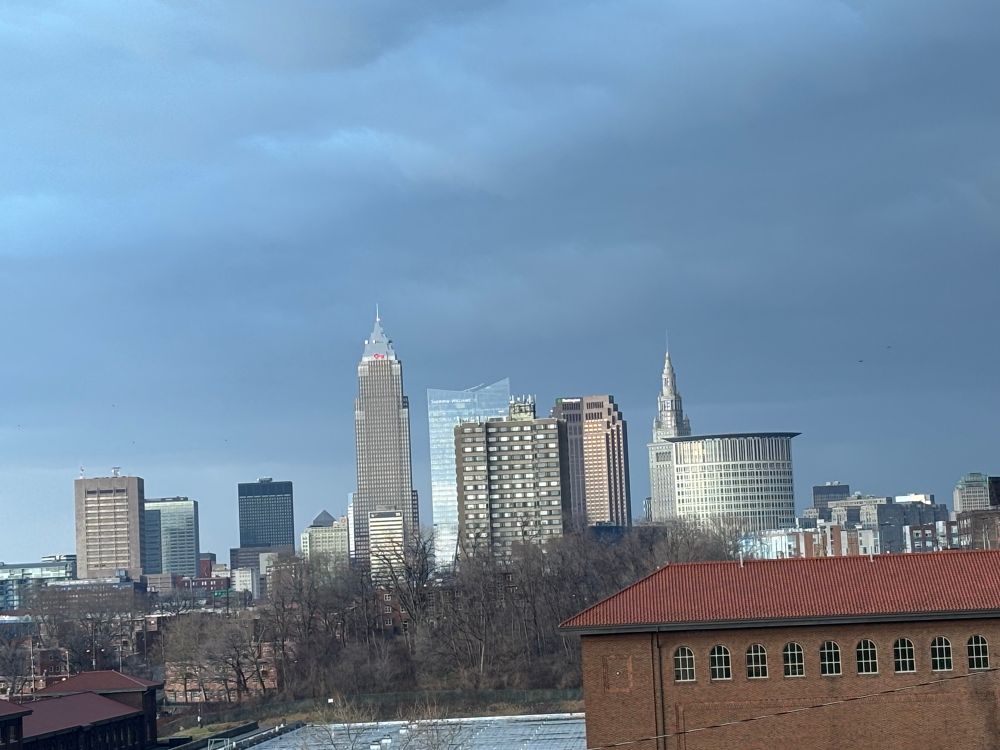 This is a photo of the Cleveland Ohio skyline with Key Tower, the Sherwin Williams building, an apartment building, the Terminal Tower and the Federal Office building against a cloudy sky. 