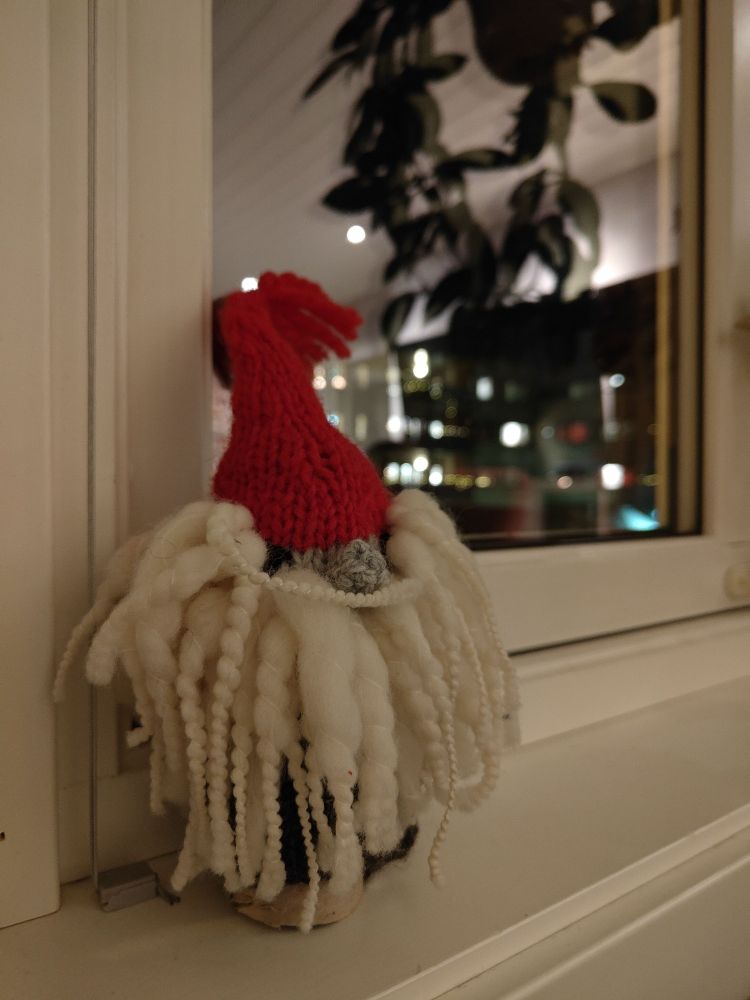 En strikket nisse med dorullkjerne og et tovet og flettet skjegg som en portugisisk vannhund.