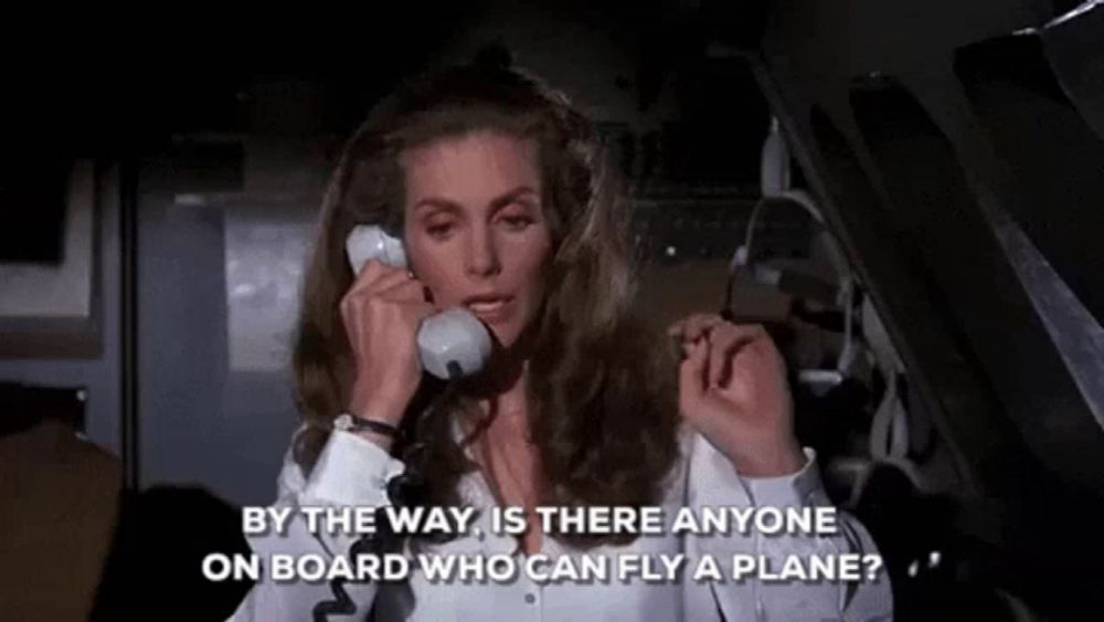 a woman on a plane talking on a phone with the words by the way is there anyone on board who can fly a plane ?