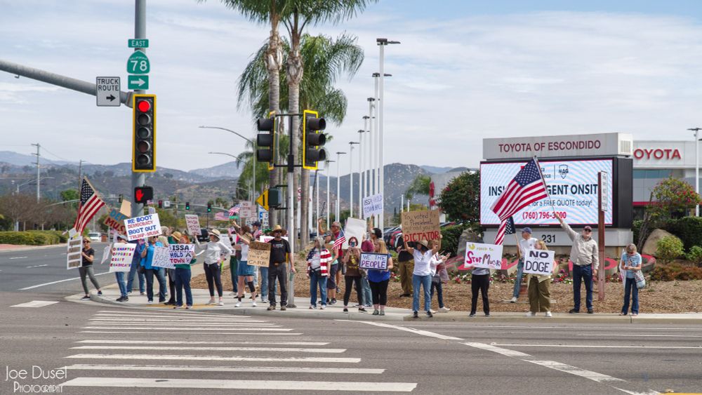 People wave signs at a protest against Congressman Darrell Issa in Escondido, CA on Feb 28, 2025. Joe Dusel Photography.