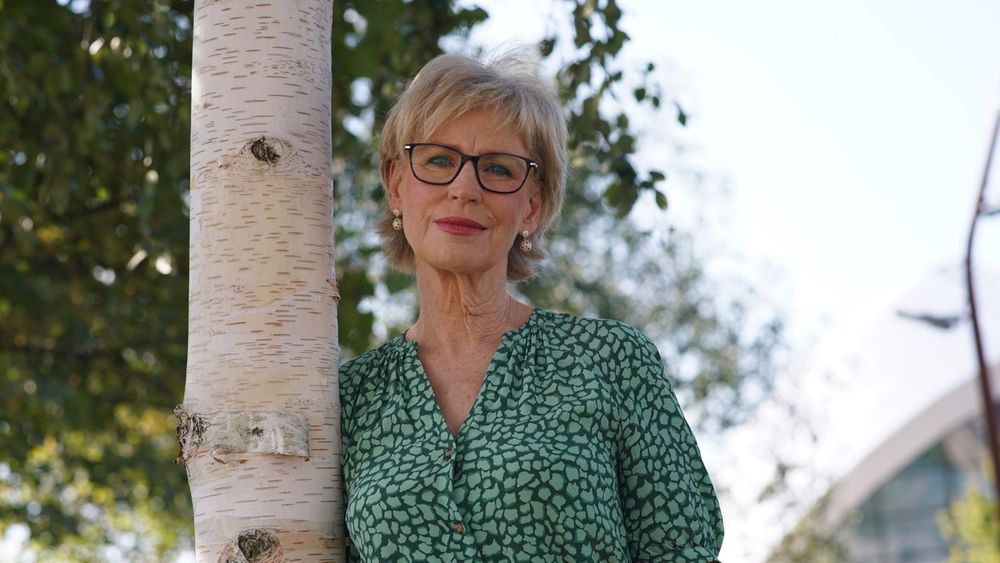 Sally stands beside tree