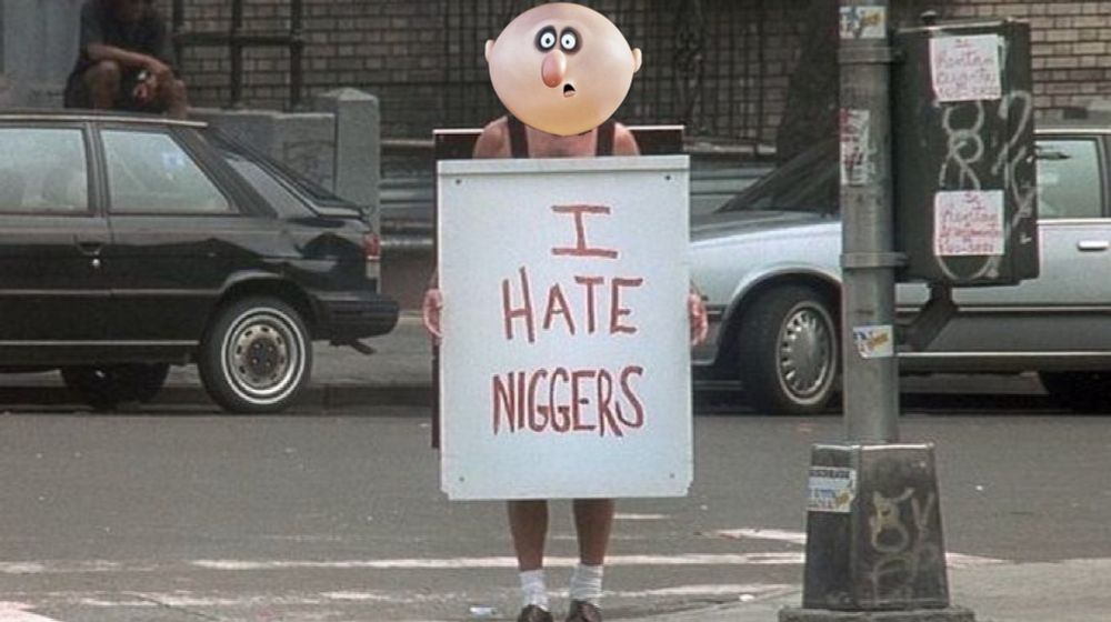 A screenshot from Die Hard With a Vengeance in which Bruce Willis is holding a panel saying « I hate n-words ». His face has been replaced with the big ugly face of Uncle Fester from the Addams Family animated series