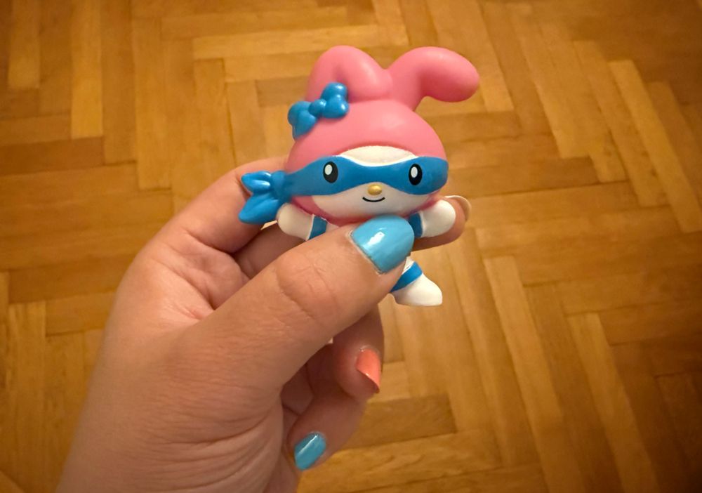 a figurine of My Melody from the Sanrio x Ninja Turtles Happy Meal collab. She has a white skin, a pink hood, and a blue bandana over her eyes