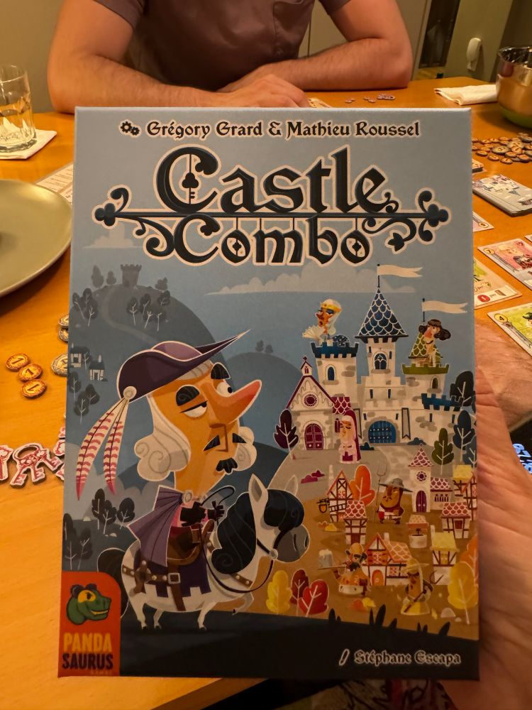 Box cover for Castle Combo, with cartoon figure of medieval man on a horse looking at a castle. 