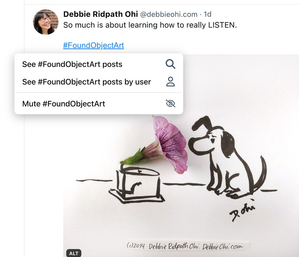 A screenshot showing a creative found object art illustration combining a real flower and a drawing, depicting a dog with its ear perked up, listening to a gramophone made from the flower's petal and stem. The artwork is signed by Debbie Ridpath Ohi.