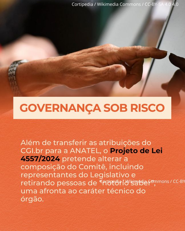 Fotografia em close-up de duas mãos de uma pessoa de pele clara, com unhas curtas e um relógio prateado no pulso esquerdo, tocando a tela de um tablet, que está fora de foco. Sobreposta à imagem, uma faixa laranja com o texto "GOVERNANÇA SOB RISCO" em letras brancas maiúsculas. Abaixo, também em um fundo laranja, um texto mais longo em fonte menor e branca: "Além de transferir as atribuições do CGI.br para a ANATEL, o Projeto de Lei 4557/2024 pretende alterar a composição do Comitê, incluindo representantes do Legislativo e retirando pessoas de notório saber, uma afronta ao caráter técnico do órgão.". No canto superior da imagem, centralizado, o crédito "Cortipedia / Wikimedia Commons / CC-BY-SA 4.0" em letras brancas.


