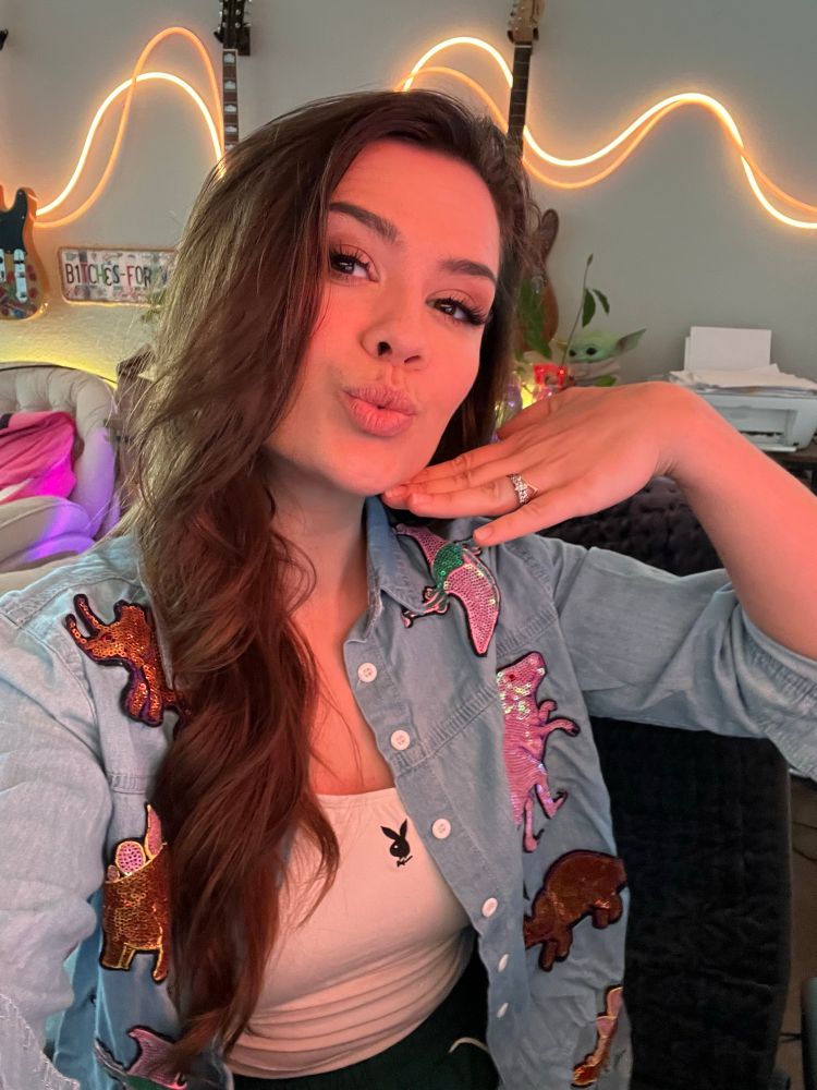 Selfie of me with my long brown hair to one side and I’m wearing a dinosaur button up