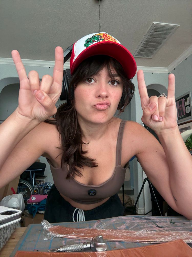 Selfie of me at my workbench throwing up devil horns and wearing a cap