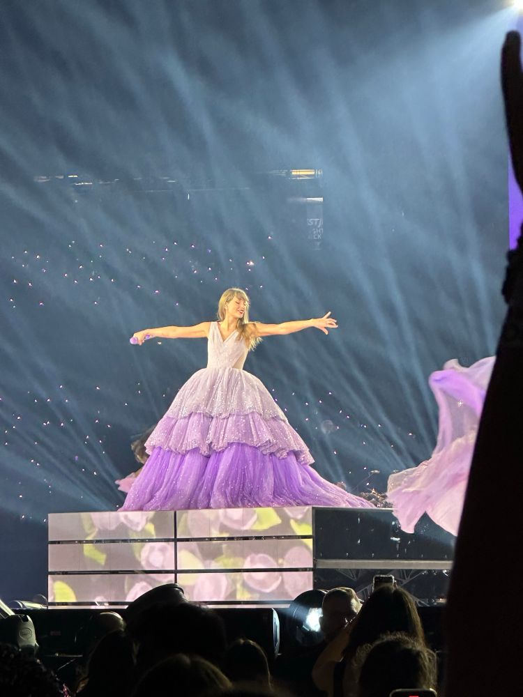 taylor swift with arms out in purple speak now dress 