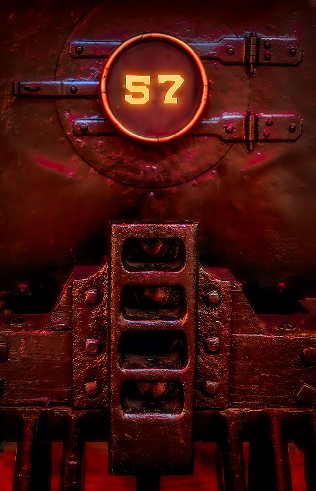 Glowing metal from the front end of a vintage train locomotive numbered 57.