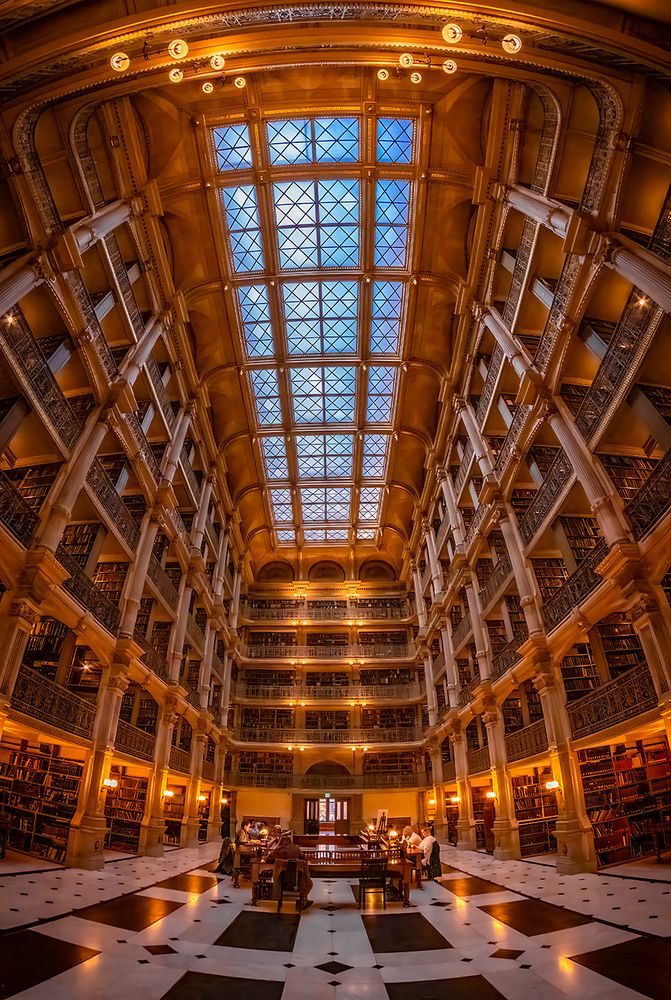 Fish-eye view of the six-story atrium, skylight, balconies, bookshelves and reading tables of Peabody Library in Baltimore, Maryland.