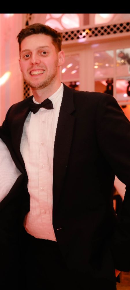 James is smiling, wearing a black tuxedo jacket, a black bow tie and a white dress shirt