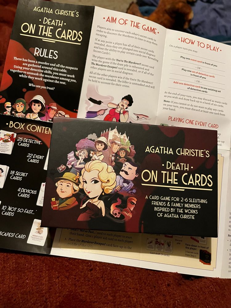 Box for “Agatha Christie’s Death on the Cards” game with rules sheet spread out behind it
