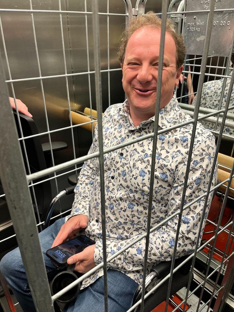 Brenno achter tralies van een rolcontainer, vermoedelijk binnen een overheidsinstelling.