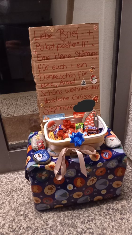 Karton mit Weihnachtspapier eingepackt, darauf eine Schale mit Schokolade und einen Karton darauf steht: Liebe Brief- + Paketpöstler*in! Eine kleine Stärkung für euch + ein Dankeschön für eure Arbeit! Schöne Weihnachten.
Herzliche Grüsse Stephanie