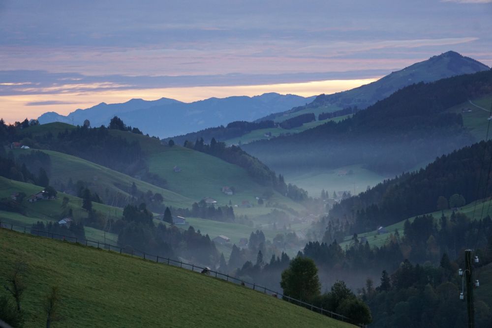 Blick in die Ostschweizer Berge mit leichtem Morgenrot und wenig Nebel im Tal