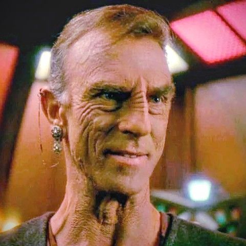 Gul Dukat has altered his body and face to appear Bajoran instead of Cardassian but it's pretty fucking obvious that it's Gul Dukat because he still really looks like Gul Dukat and you bet your ass he sounds EXACTLY like Gul Dukat and you show me a Bajoran who doesn't know EXACTLY who the fuck Gul Dukat is when they see him. 