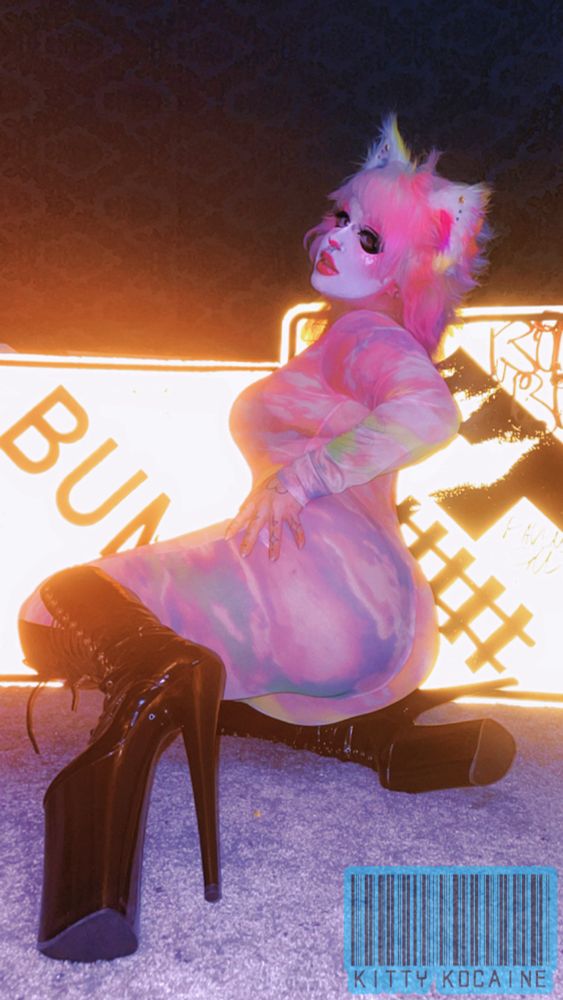 Kitty posing infront of street signs, wearing a rainbow mesh bodysuit and black 10 inch pleaser heels
