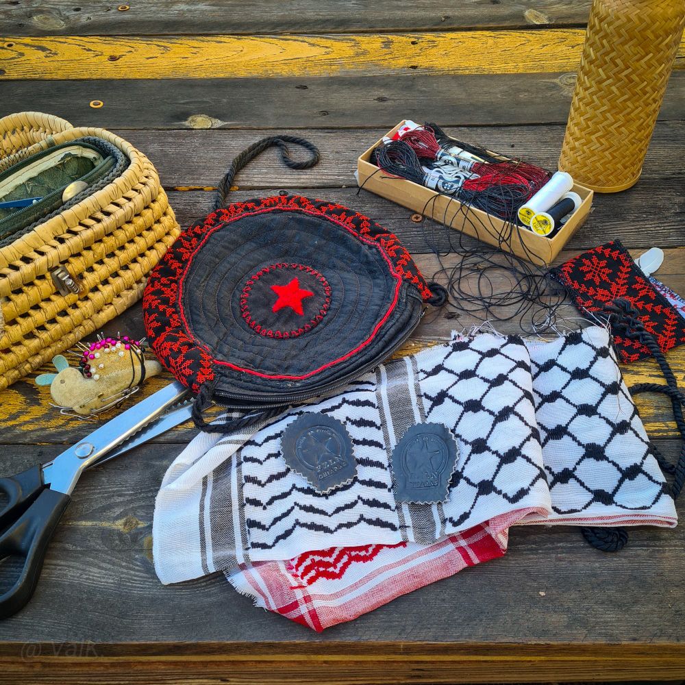 Photo de tout ce qui est décrit dans le message, le tout posé sur les planches d'une table, entouré de fils à broder et trousse à outils en vannerie et thermos recouvert d'une autre vannerie. 
La pochette, ronde et noire, au centre de l'image, arbore un patch zapatiste avec une étoile rouge au centre et de la broderie traditionnelle palestinienne, tatreez, appliquée sur son pourtour. 