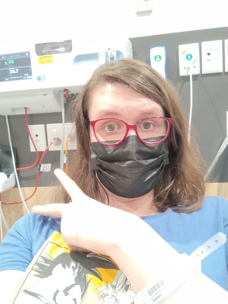 really cute girl in hospital, wearing red glasses and a face mask, hospital machinery is viewable behind her