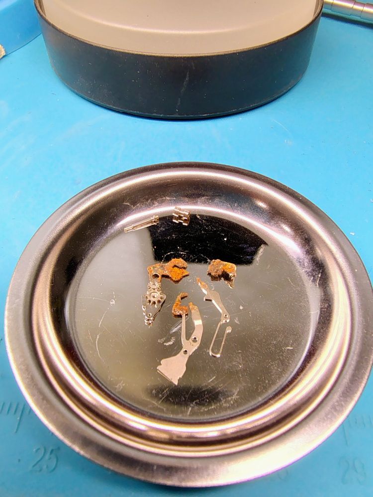 The dismantled keyless works parts infected with rust