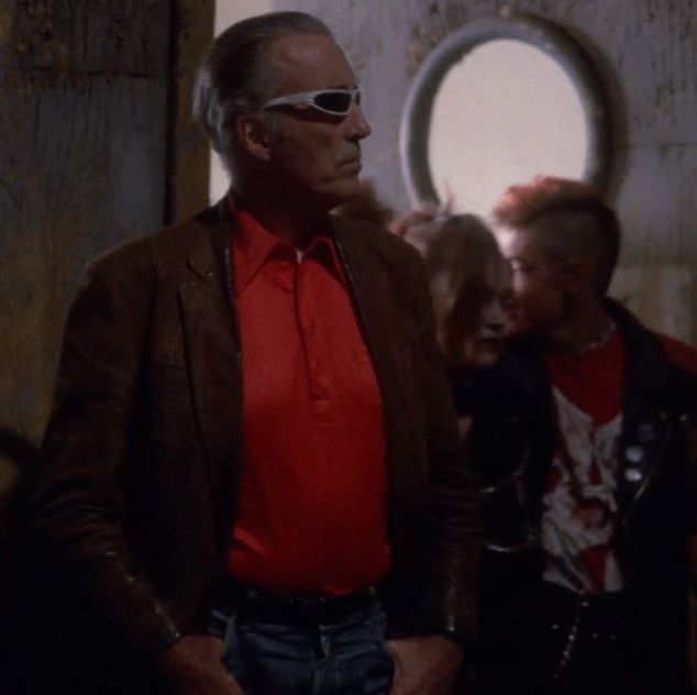 An older gentleman wearing new wave sunglasses with his bright red polo shirt