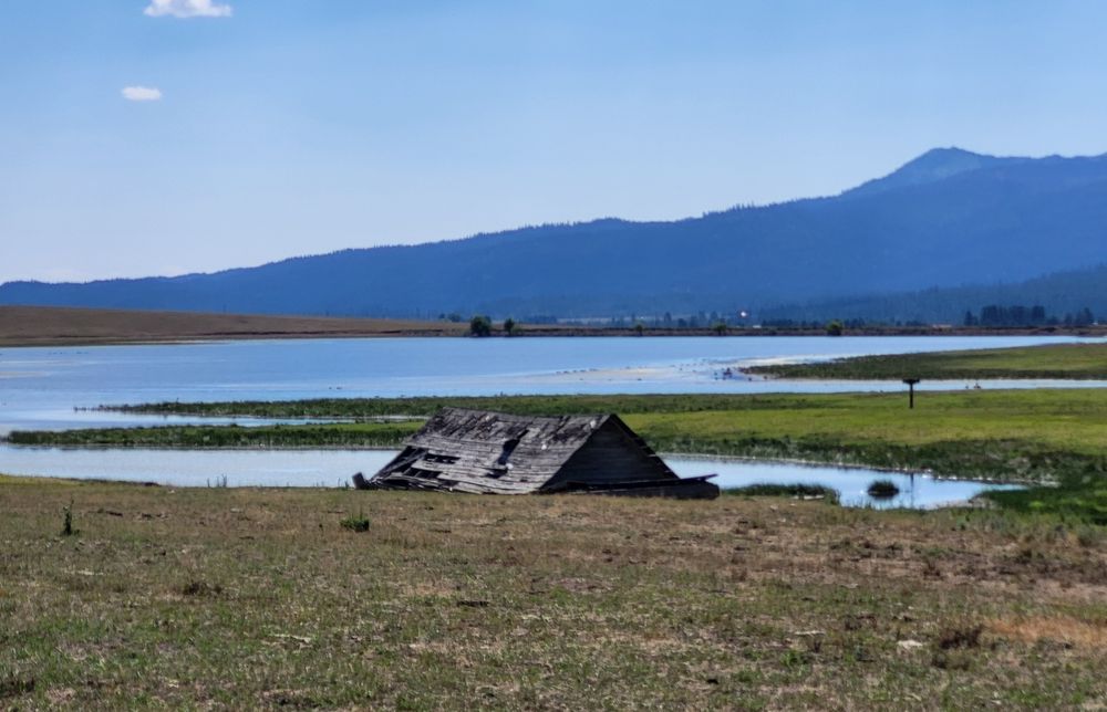 A collapsed building with nothing left but the roof, and the roof is full of holes. But there is a great view of a lake and mountains.
