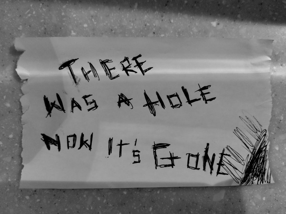 A piece of paper, written in black ink on it is: "There was a hole now it's gone"