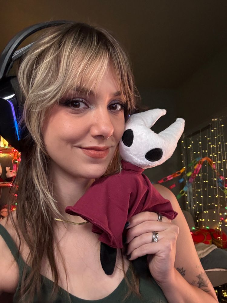 Ellie is smiling in a selfie, smushing a hornet plush against her face