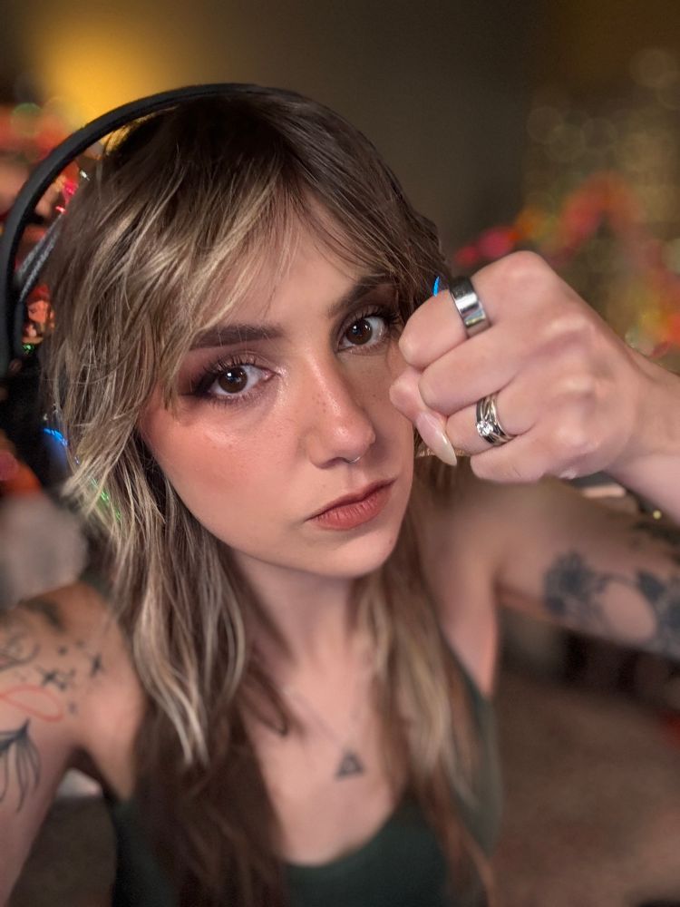 Ellie is straight faced in a selfie holding her fist up close to the camera in a threatening way