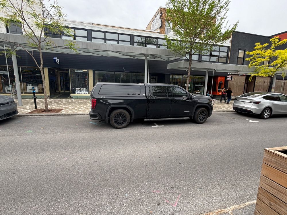 Un gros VUS stationné à cheval entre 2 places