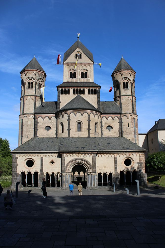 Die Kirche des Klosters Maria Laach von der Vorderseite. Es hat in der Mitte einen großen und links und rechts daneben je einen kleineren Turm. Unten in der Mitte gibt es einen Durchgang, der ins Innere der Kirche führt.