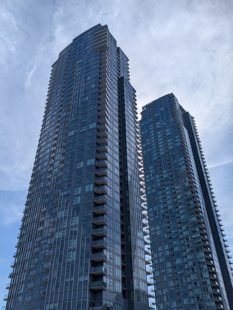 Blue skyscrapers against a backdrop of blue skies and high clouds.