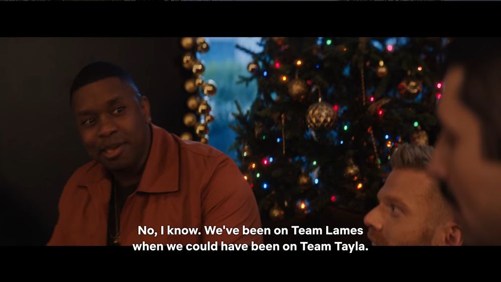 A shot from the film "Meet Me Next Christmas" where the Pentatonix are saying "No, I know. We've been on Team Lames [Layla & James] when we could have been on Team Tayla [Teddy & James]."