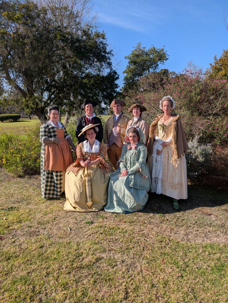a group of people dressed in revolutionary war-era clothing, posing for a photo